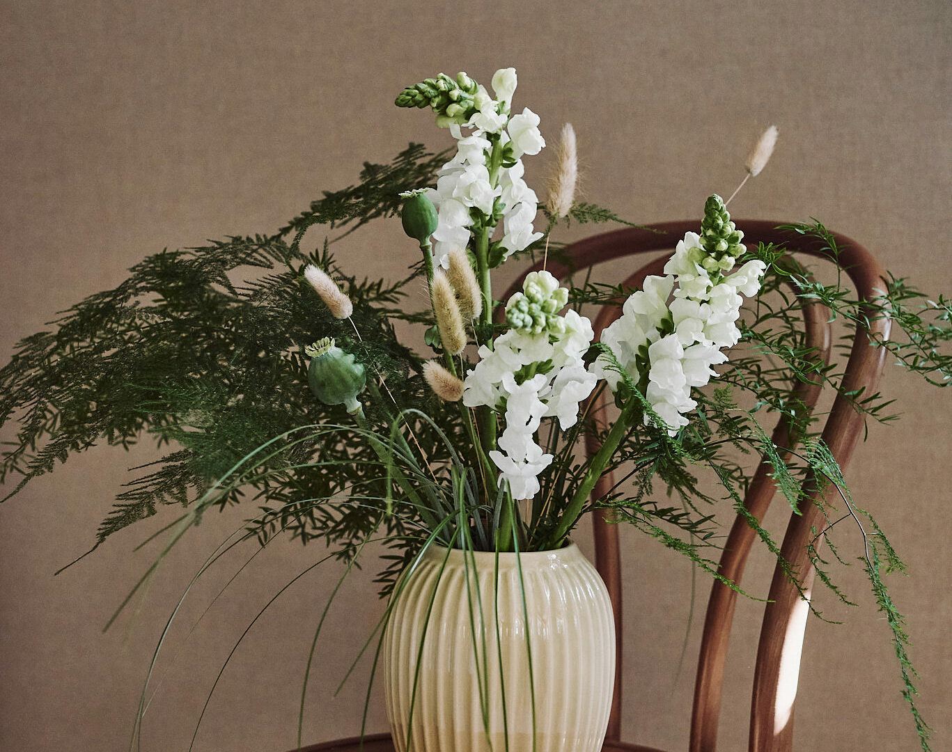 Lantlig blombukett med lejongap, vallmo, asparagus, lagurus och gräs.