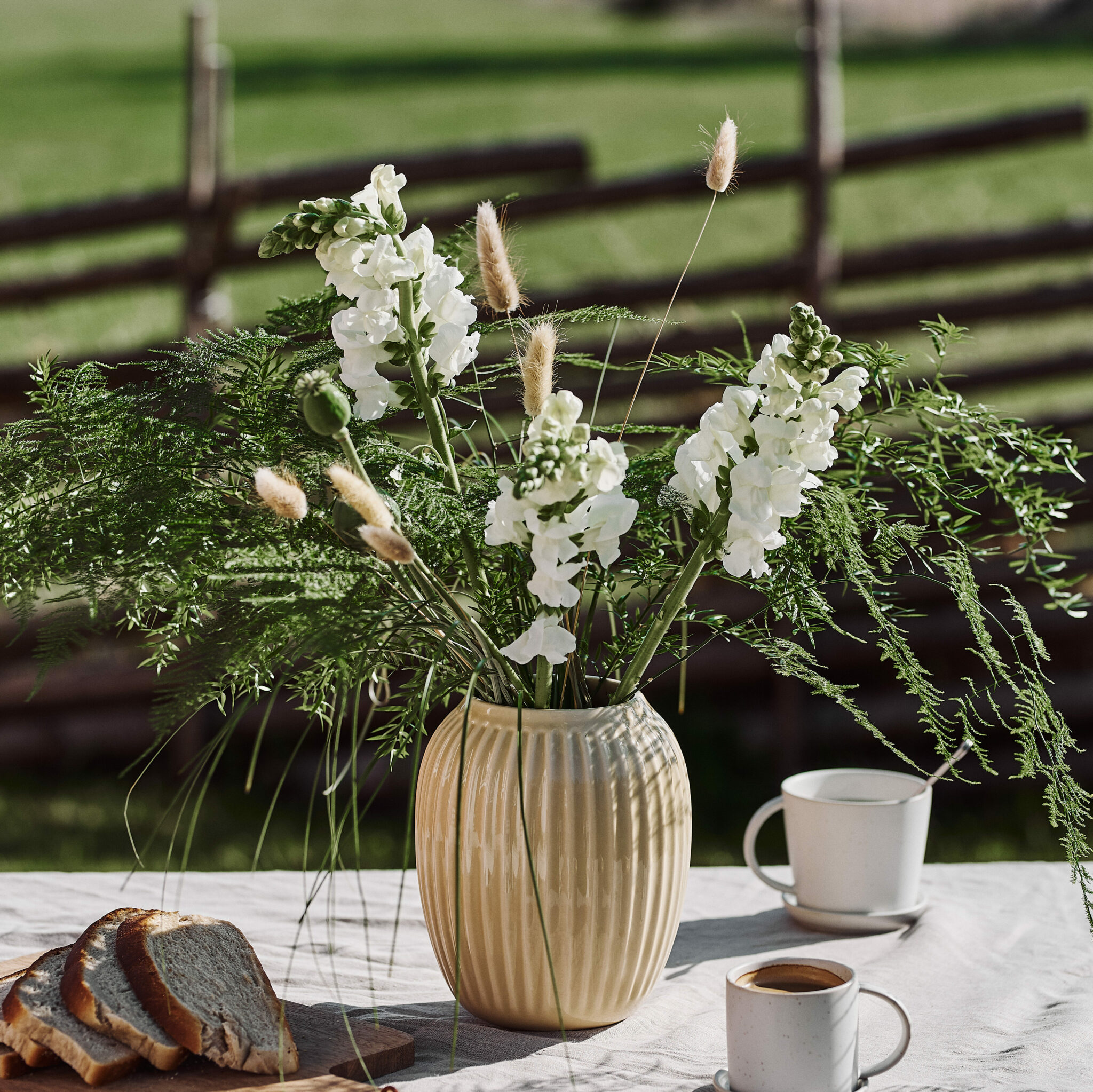 Lantlig blombukett med lejongap, vallmo, asparagus, lagurus och gräs.